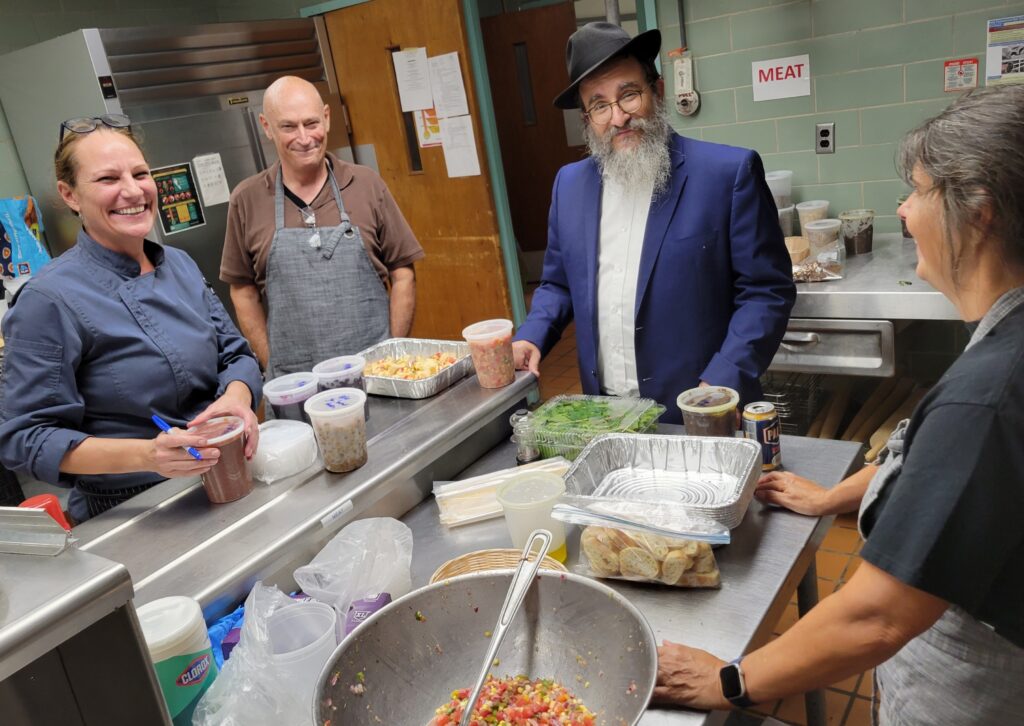 Four people pause during 2022 J'la Gala kosher kitchen preparations for a photo, including Chef Maureen Holt and Rabbi Yossi Friedman