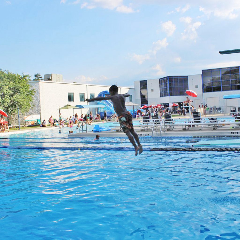 Boy in the air while jumping into the pool