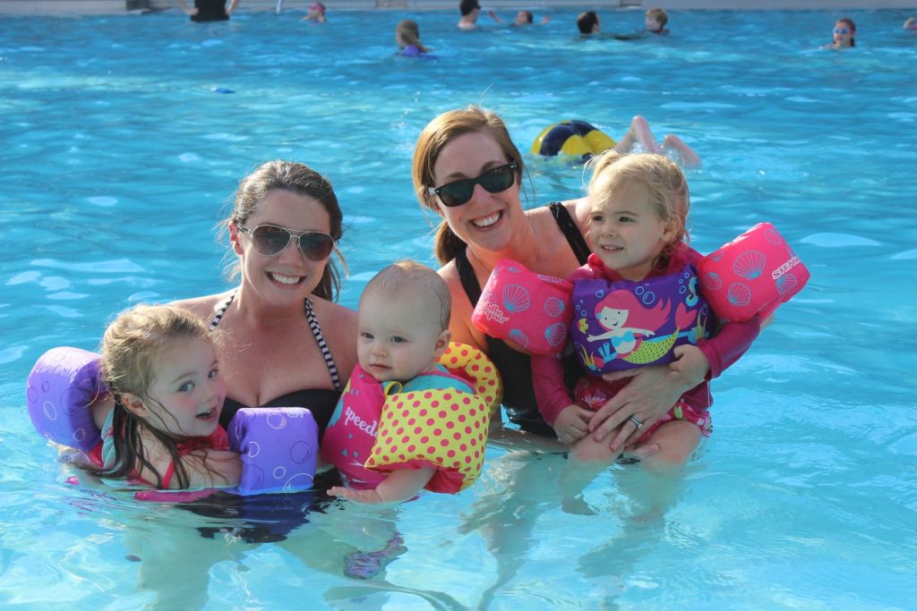 Two mothers holding their babies in the pool