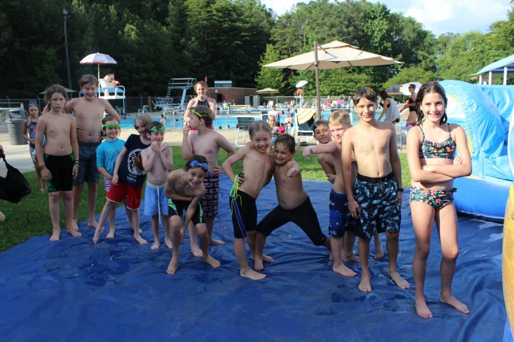 A group of children standing together on a tarp in the pool area of the LJCC