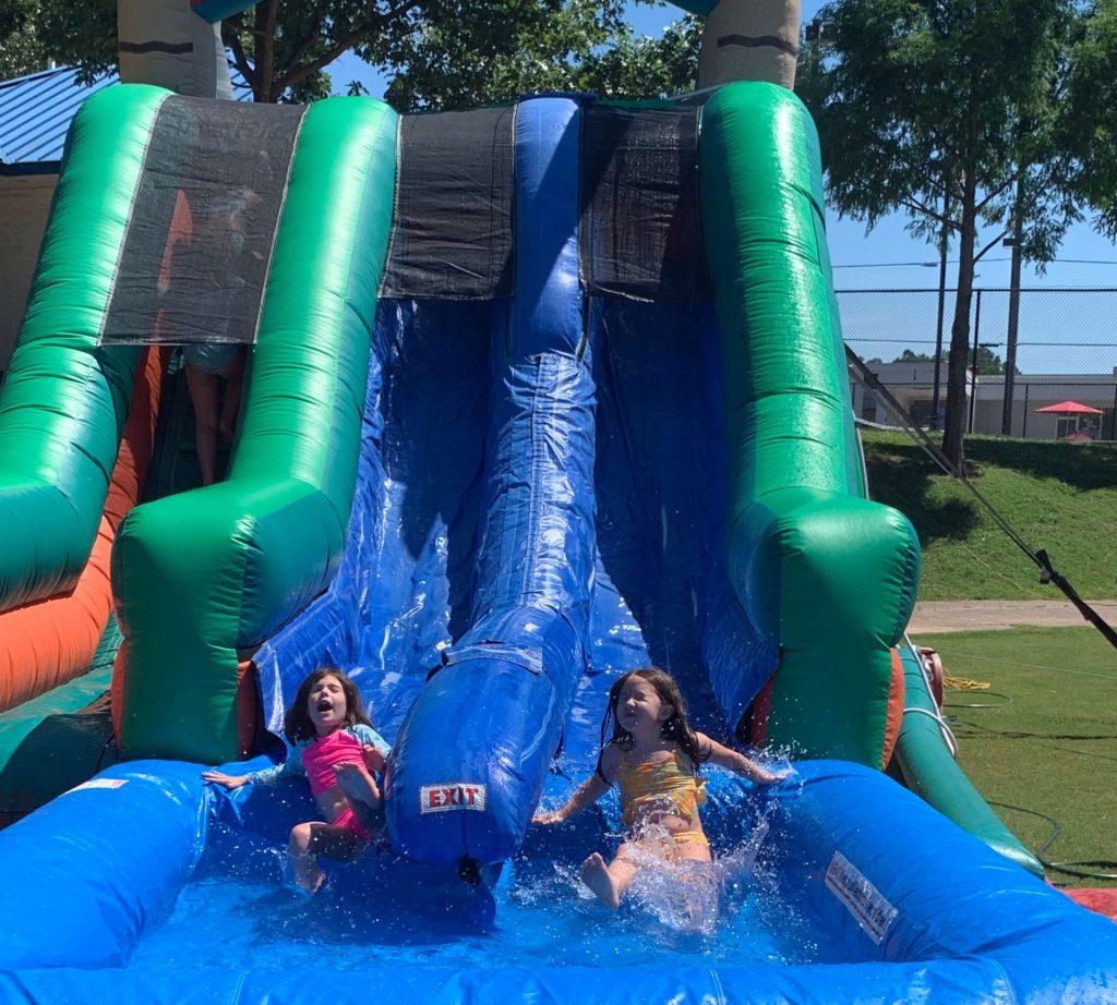 Two children sliding down a double inflatable waterslide